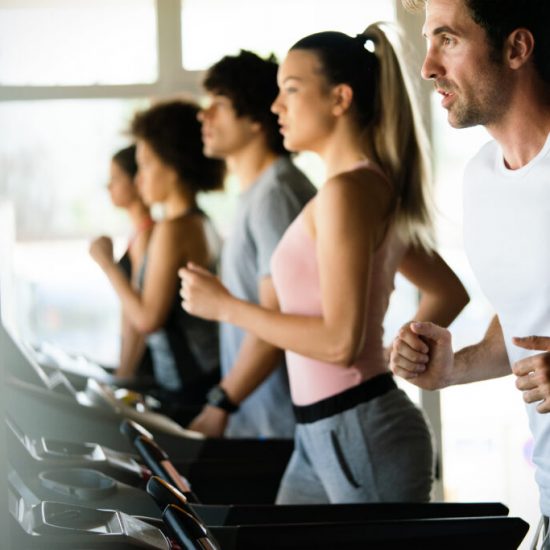 Group of young people running on treadmills in modern sport gym